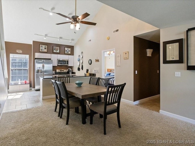 335 Charleston Dr Unit 3B, Lake Ozark, MO 65049 - dining area with a ceiling fan, rail lighting, high vaulted ceiling, baseboards, and light colored carpet