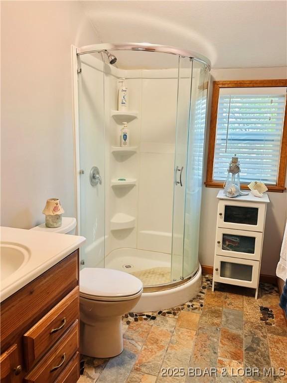 33722 Waterfront Dr, Stover, MO 64078 - bathroom featuring a stall shower, vanity, stone finish floors, and toilet