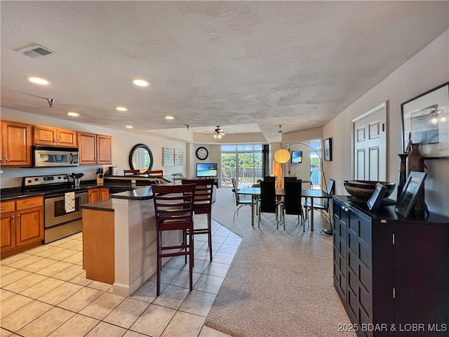 4800 Eagleview Dr Unit 6104, Osage Beach, MO 65065 - kitchen featuring appliances with stainless steel finishes, dark countertops, a breakfast bar area, recessed lighting, and brown cabinetry