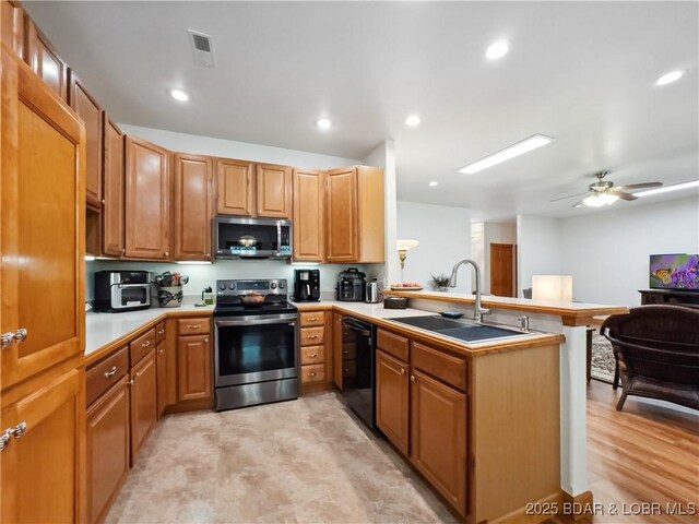 204 Wellington Ln, Laurie, MO 65037 - kitchen featuring appliances with stainless steel finishes, a sink, a peninsula, light countertops, and a ceiling fan