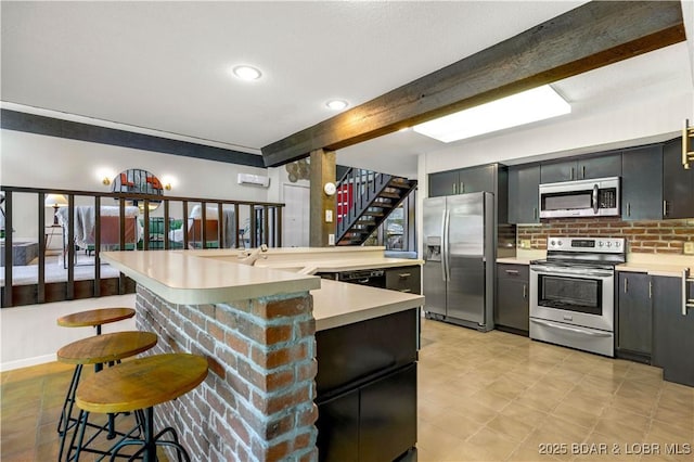 491 Walkers Cay, Osage Beach, MO 65065 - kitchen with appliances with stainless steel finishes, light countertops, beamed ceiling, a breakfast bar area, and a sink