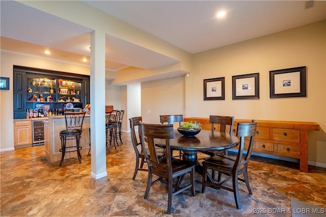 55 Shagbark Dr, Sunrise Beach, MO 65079 - dining space featuring wine cooler, bar area, baseboards, recessed lighting, and ornamental molding