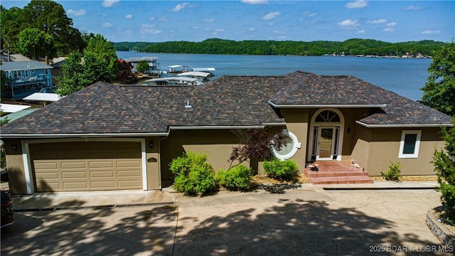 55 Shagbark Dr, Sunrise Beach, MO 65079 - ranch-style house featuring stucco siding, a water view, an attached garage, and driveway