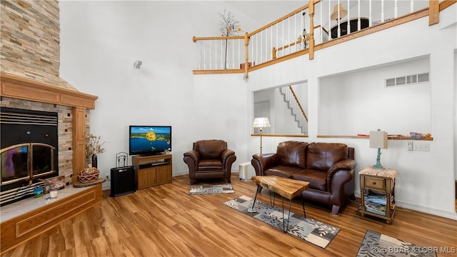 1396 Robyn Ct, Osage Beach, MO 65065 - living room with a glass covered fireplace, wood finished floors, a high ceiling, baseboards, and stairs