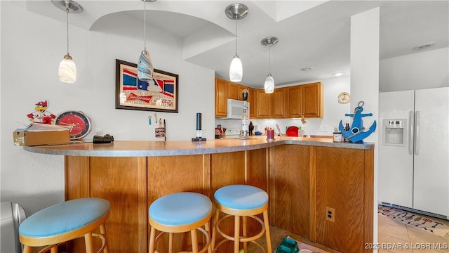 1396 Robyn Ct, Osage Beach, MO 65065 - kitchen featuring white appliances, brown cabinetry, decorative light fixtures, a kitchen breakfast bar, and light tile patterned floors