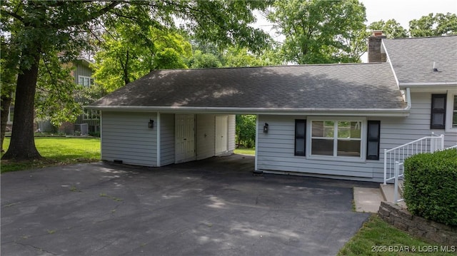 288 Oak Ridge Rd, Lake Ozark, MO 65049 - view of front of house featuring a shingled roof, asphalt driveway, a chimney, and an attached carport