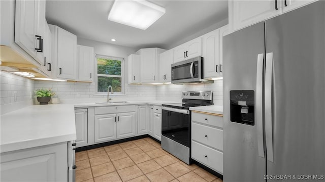 288 Oak Ridge Rd, Lake Ozark, MO 65049 - kitchen with appliances with stainless steel finishes, a sink, light tile patterned floors, tasteful backsplash, and white cabinetry