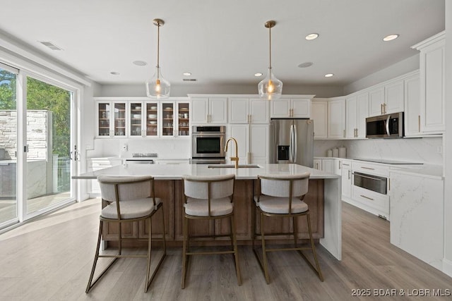 584 Black Hawk Dr, Lake Ozark, MO 65049 - kitchen with stainless steel appliances, a sink, backsplash, white cabinetry, and light wood-type flooring