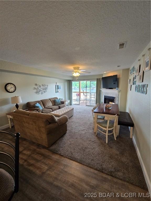 1481 Ledges Dr Unit 221, Osage Beach, MO 65065 - living room featuring a textured ceiling, a fireplace, ceiling fan, wood finished floors, and baseboards