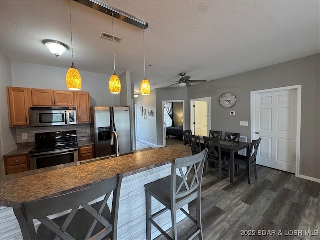 275 Flynn Rd Unit 207, Lake Ozark, MO 65049 - kitchen featuring appliances with stainless steel finishes, a breakfast bar area, dark wood-type flooring, a textured ceiling, and ceiling fan