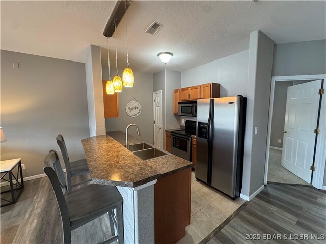 275 Flynn Rd Unit 207, Lake Ozark, MO 65049 - kitchen with stainless steel appliances, dark countertops, a peninsula, a kitchen breakfast bar, and light wood-type flooring