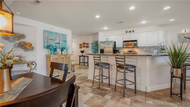 364 Cedar Heights Dr Unit 2D, Camdenton, MO 65020 - kitchen featuring stainless steel appliances, a kitchen bar, white cabinetry, backsplash, and recessed lighting