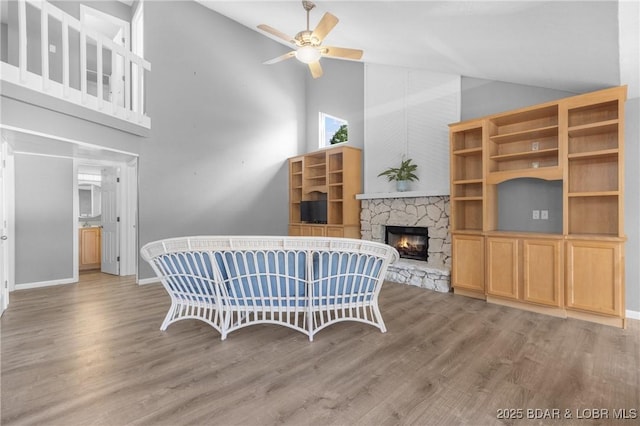 25 Redwood Ct, Sunrise Beach, MO 65079 - living room featuring high vaulted ceiling, ceiling fan, wood finished floors, a stone fireplace, and baseboards