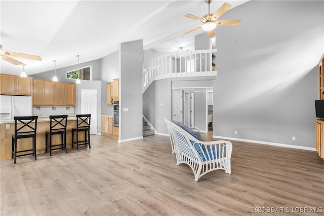 25 Redwood Ct, Sunrise Beach, MO 65079 - kitchen with a ceiling fan, white refrigerator with ice dispenser, high vaulted ceiling, a breakfast bar area, and light wood finished floors