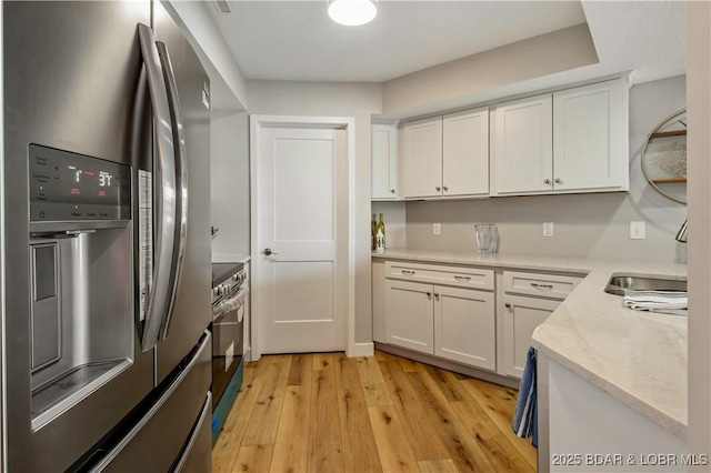 701 Cedar Rd Unit 1A, Lake Ozark, MO 65049 - kitchen with appliances with stainless steel finishes, light wood-style floors, white cabinetry, and light stone counters