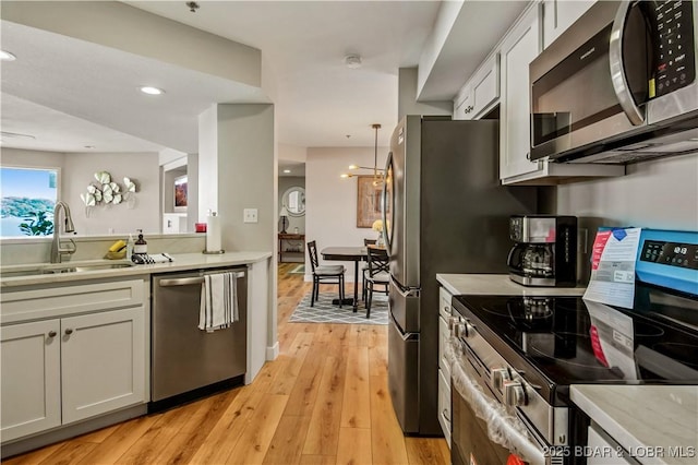 701 Cedar Rd Unit 1A, Lake Ozark, MO 65049 - kitchen with stainless steel appliances, a sink, light countertops, white cabinetry, and light wood-style floors