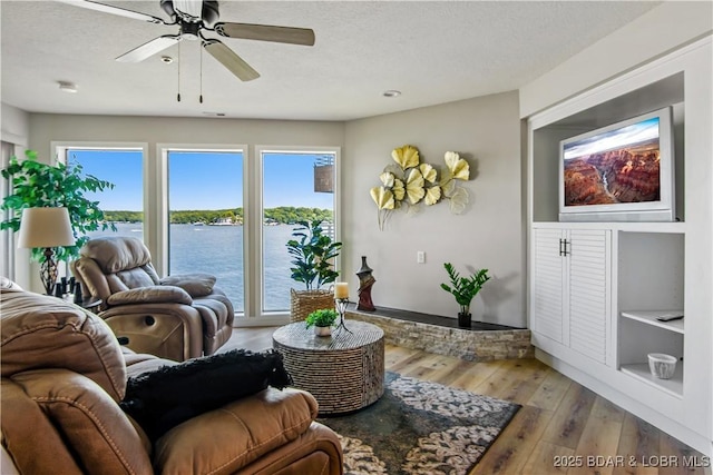 701 Cedar Rd Unit 1A, Lake Ozark, MO 65049 - living room featuring hardwood / wood-style flooring, a water view, a ceiling fan, a textured ceiling, and baseboards