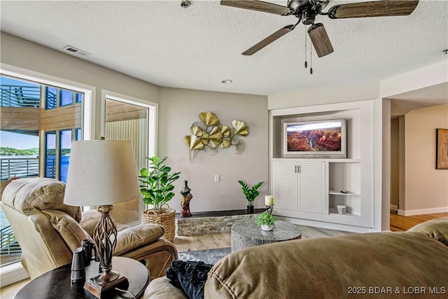 701 Cedar Rd Unit 1A, Lake Ozark, MO 65049 - living area featuring plenty of natural light, wood finished floors, a textured ceiling, ceiling fan, and baseboards