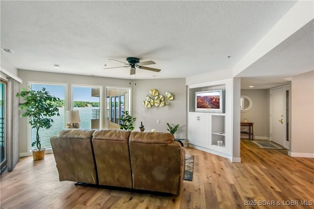 701 Cedar Rd Unit 1A, Lake Ozark, MO 65049 - living room with ceiling fan, a textured ceiling, light wood-style floors, plenty of natural light, and baseboards