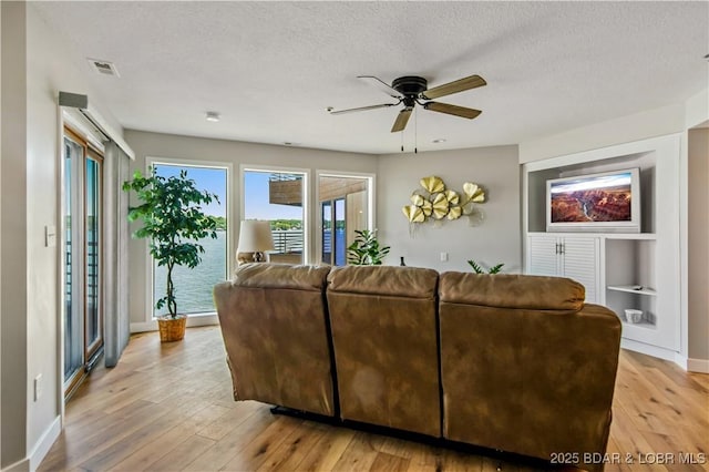 701 Cedar Rd Unit 1A, Lake Ozark, MO 65049 - living room with ceiling fan, light wood-type flooring, baseboards, and a textured ceiling