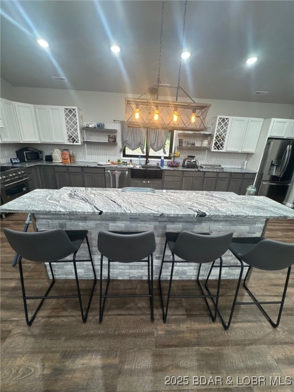 1760 Deans Creek Rd, Richland, MO 65556 - kitchen featuring appliances with stainless steel finishes, decorative backsplash, a kitchen breakfast bar, white cabinetry, and light stone countertops