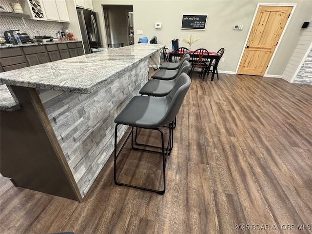 1760 Deans Creek Rd, Richland, MO 65556 - kitchen featuring stainless steel refrigerator with ice dispenser, dark wood finished floors, baseboards, tasteful backsplash, and a breakfast bar
