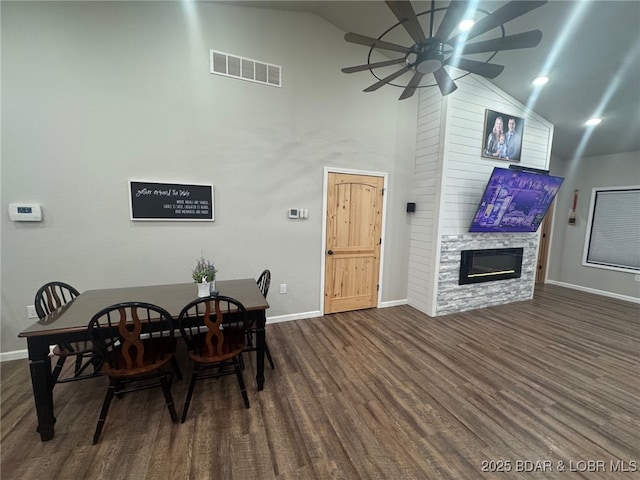 1760 Deans Creek Rd, Richland, MO 65556 - dining room featuring ceiling fan, baseboards, dark wood-style floors, a stone fireplace, and high vaulted ceiling