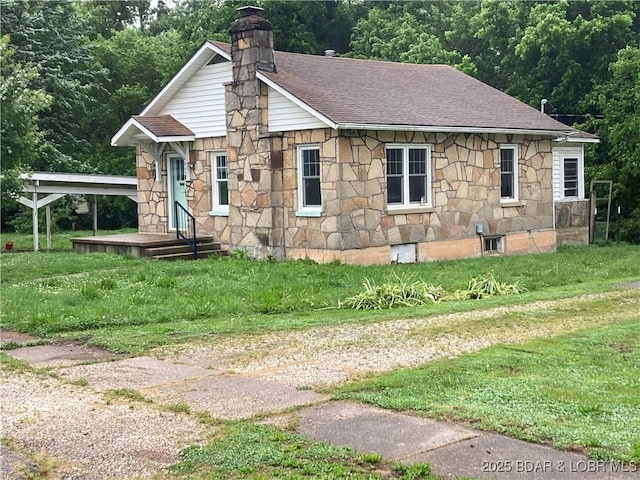 203 S Hunter St, Versailles, MO 65084 - view of front facade with stone siding, roof with shingles, a chimney, and a carport