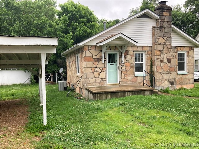 203 S Hunter St, Versailles, MO 65084 - bungalow-style home with a front yard, stone siding, and a chimney