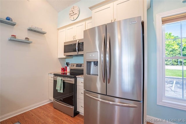 4066 Horseshoe Bend Pkwy Unit 3A, Lake Ozark, MO 65049 - kitchen featuring appliances with stainless steel finishes, light wood-type flooring, white cabinets, and baseboards