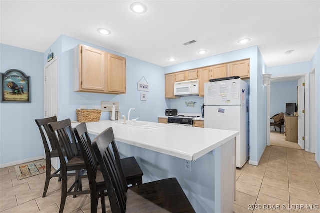 289 Charleston Dr Unit 2B, Lake Ozark, MO 65049 - kitchen with white appliances, light brown cabinets, a sink, a peninsula, and a kitchen bar