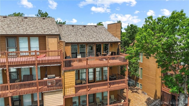 111 Rock Dove Ln Unit 3A, Camdenton, MO 65020 - back of property featuring a shingled roof, a chimney, a balcony, and central air condition unit