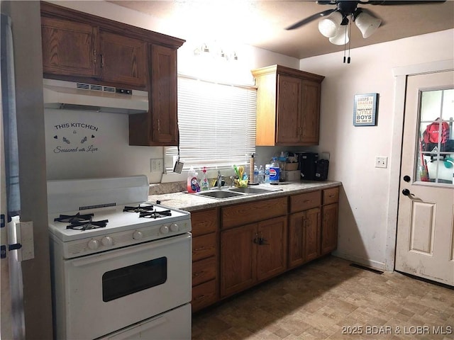 203 3rd St, Stover, MO 65078 - kitchen with white gas range, a sink, under cabinet range hood, a ceiling fan, and light countertops