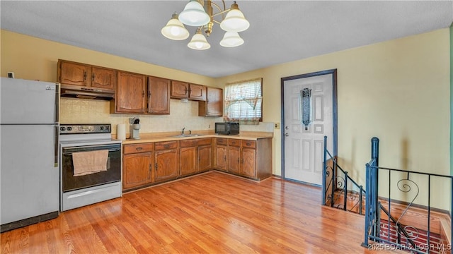 864 Four Waters Dr, Sunrise Beach, MO 65079 - kitchen featuring freestanding refrigerator, electric range oven, under cabinet range hood, a sink, and a chandelier