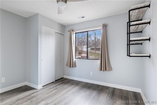 98 Jonathan Dr Unit 4C, Lake Ozark, MO 65049 - unfurnished bedroom with wood finished floors, a closet, baseboards, a textured ceiling, and a ceiling fan