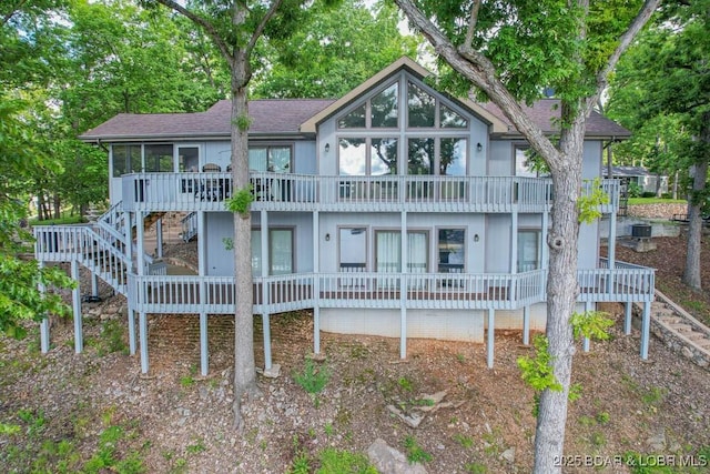 42 Rhine River Rd, Sunrise Beach, MO 65079 - chalet / cabin featuring stairs, a sunroom, a shingled roof, and view of wooded area