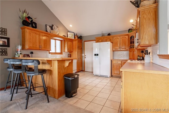 42 Rhine River Rd, Sunrise Beach, MO 65079 - kitchen with white fridge with ice dispenser, a peninsula, vaulted ceiling, decorative backsplash, and a kitchen breakfast bar