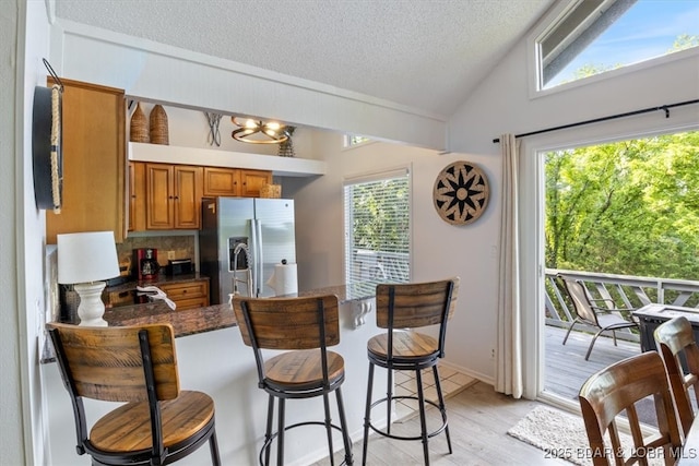 73 Ship Dock Ln, Osage Beach, MO 65065 - kitchen with stainless steel fridge, brown cabinets, a peninsula, a textured ceiling, and light wood-style floors