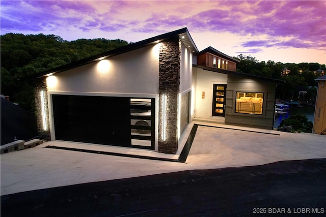 186 Frudeger Rd, Lake Ozark, MO 65049 - modern home featuring stone siding, stucco siding, a garage, and driveway