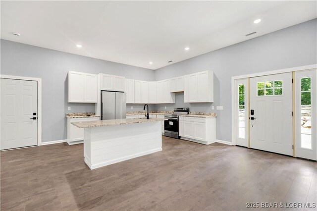 19580 Wonderland Rd, Rocky Mount, MO 65072 - kitchen with appliances with stainless steel finishes, a kitchen island with sink, white cabinetry, wood finished floors, and recessed lighting