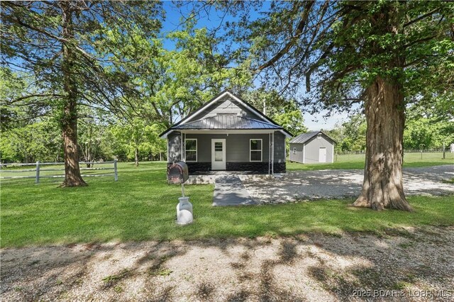 47 Hittridge Rd, Eldon, MO 65026 - shotgun-style home featuring covered porch, metal roof, and an outbuilding