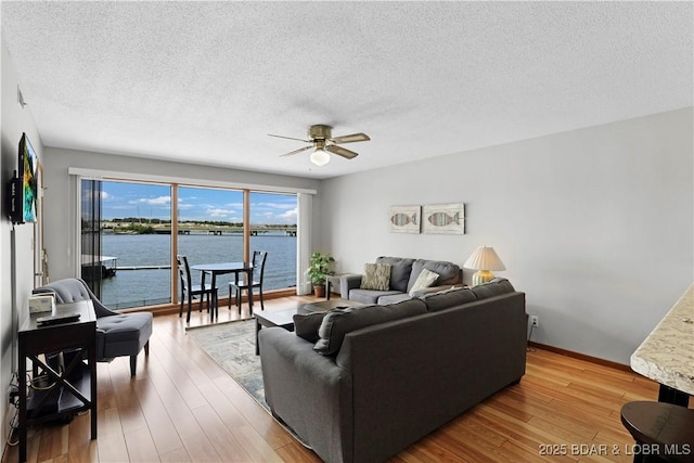 875 Parkside Pl Unit B102, Osage Beach, MO 65065 - living room featuring a ceiling fan, a textured ceiling, wood finished floors, baseboards, and a water view
