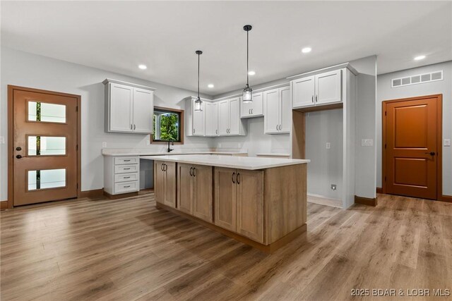 55 Turn Bridge Ln, Porto Cima, MO 65079 - kitchen featuring light wood finished floors, a kitchen island, baseboards, a sink, and white cabinetry