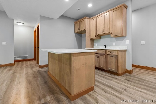 55 Turn Bridge Ln, Porto Cima, MO 65079 - kitchen featuring light wood finished floors, light countertops, baseboards, a kitchen island, and a sink