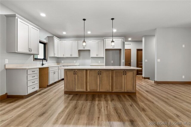 55 Turn Bridge Ln, Porto Cima, MO 65079 - kitchen featuring baseboards, light wood-type flooring, a center island, a sink, and recessed lighting
