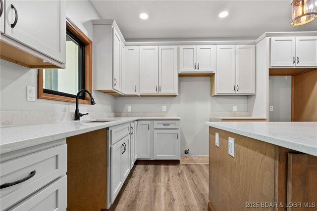 55 Turn Bridge Ln, Porto Cima, MO 65079 - kitchen with a sink, light stone counters, light wood-style flooring, recessed lighting, and white cabinetry