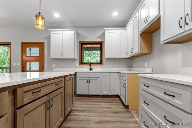 55 Turn Bridge Ln, Porto Cima, MO 65079 - kitchen with decorative light fixtures, a sink, light stone countertops, light wood finished floors, and recessed lighting
