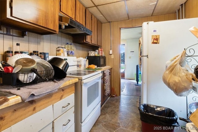 413 E 3rd St, Eldon, MO 65026 - kitchen with white appliances, under cabinet range hood, brown cabinets, wood walls, and light countertops