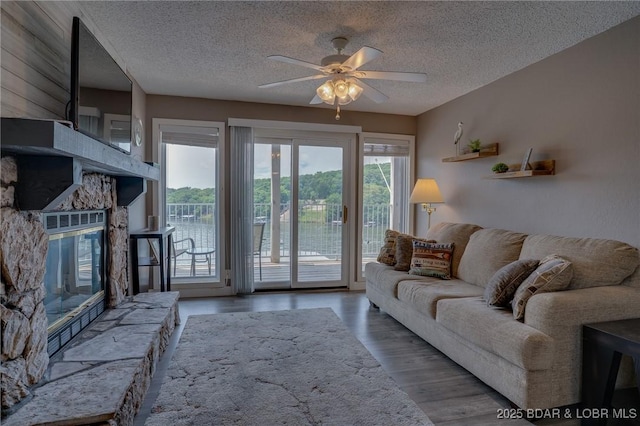 28 Wheel House Cir Unit A-4, Four Seasons, MO 65049 - living room with a textured ceiling, a ceiling fan, wood finished floors, and a stone fireplace