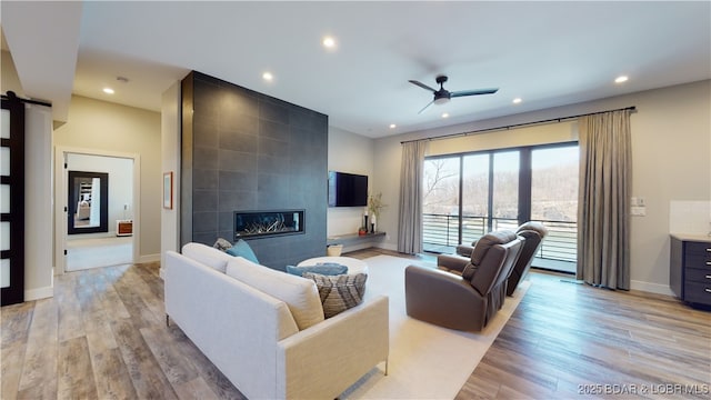 481 Comanche Rd, Lake Ozark, MO 65049 - living room with ceiling fan, a tiled fireplace, recessed lighting, light wood-type flooring, and a barn door